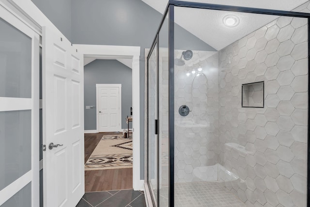 bathroom featuring tile patterned flooring, a shower stall, and lofted ceiling