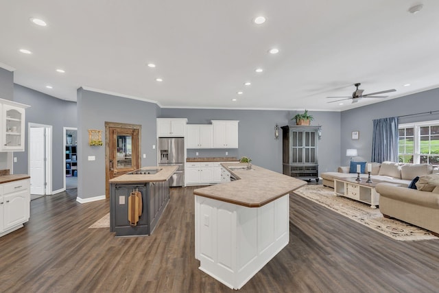 kitchen with stainless steel fridge, a ceiling fan, recessed lighting, white cabinetry, and a large island with sink