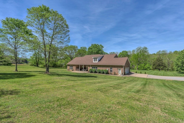 view of front of house featuring an attached garage, brick siding, driveway, and a front yard
