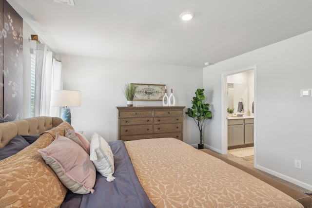 bedroom featuring light carpet, baseboards, and ensuite bathroom