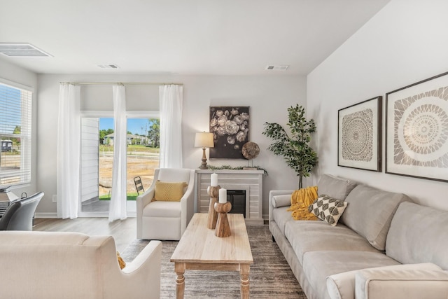 living area featuring a glass covered fireplace, wood finished floors, and visible vents