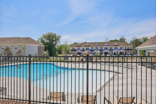 pool featuring a patio area, fence, and a residential view