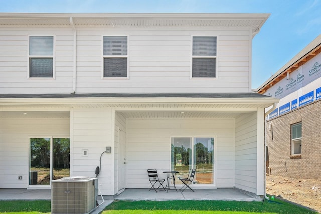 rear view of property with a shingled roof, a patio, and central AC unit