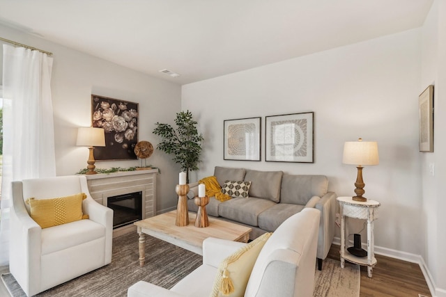 living area with baseboards, a glass covered fireplace, wood finished floors, and visible vents