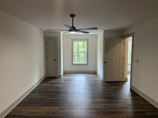 spare room featuring baseboards, dark wood finished floors, and ceiling fan