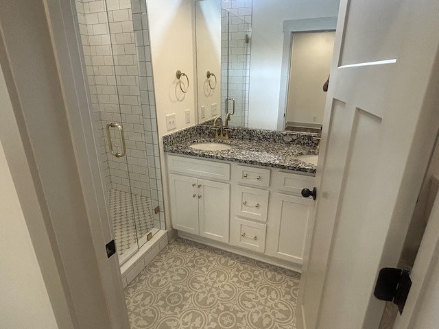 full bath featuring double vanity, a sink, and a stall shower