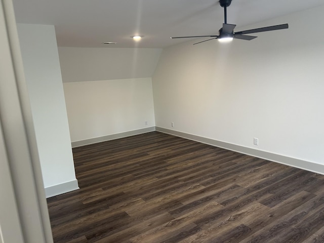 spare room with vaulted ceiling, baseboards, a ceiling fan, and dark wood-type flooring