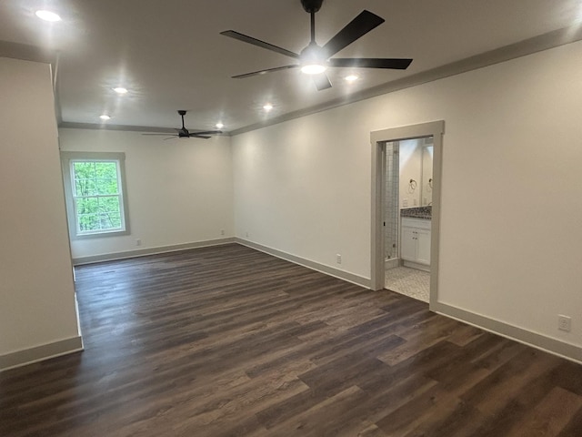spare room featuring baseboards, a ceiling fan, and dark wood-type flooring