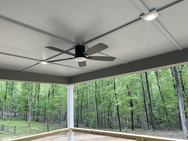 exterior details with fence, ceiling fan, and a wooded view