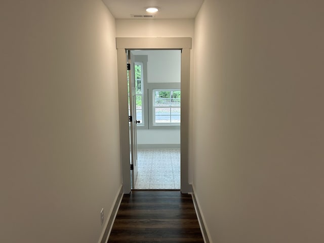 hallway with baseboards, dark wood-type flooring, and visible vents