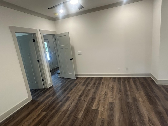 spare room featuring baseboards, a ceiling fan, and dark wood finished floors