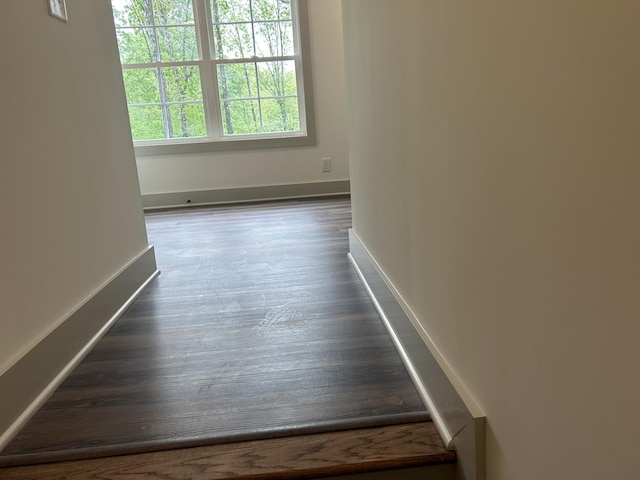 empty room featuring baseboards and dark wood-type flooring