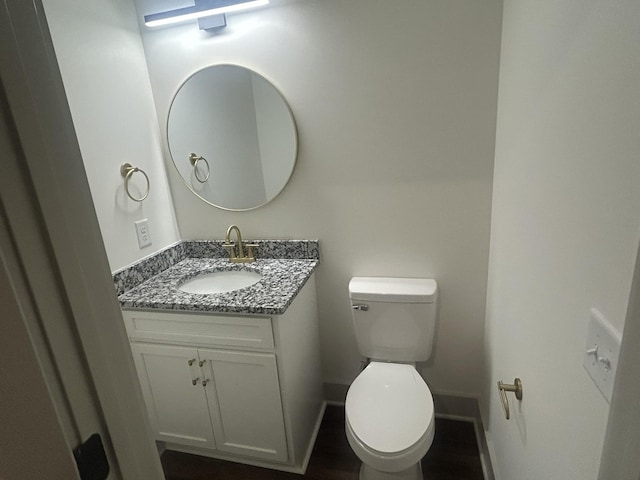 half bathroom featuring vanity, baseboards, and toilet