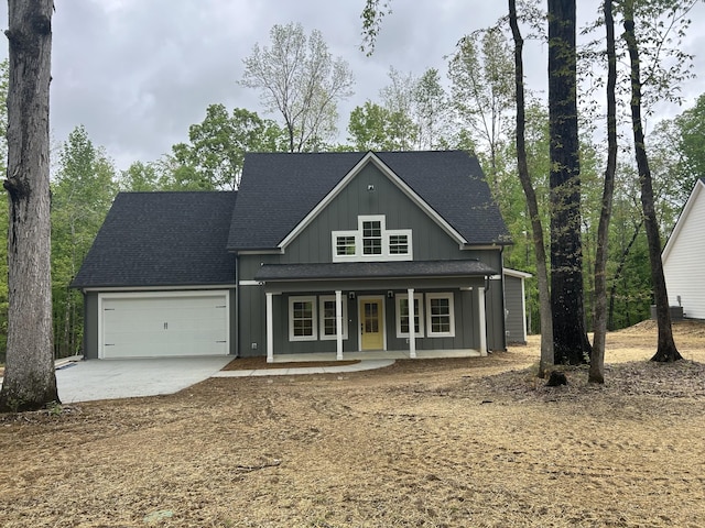 view of front of house with roof with shingles, covered porch, an attached garage, and concrete driveway