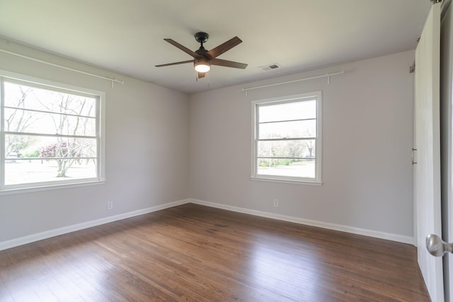 empty room featuring dark wood-style floors, baseboards, a ceiling fan, and visible vents