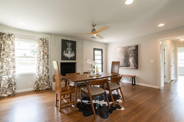 dining space featuring plenty of natural light, dark wood-style floors, a fireplace, and ceiling fan