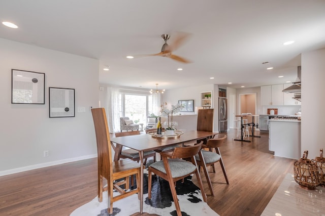 dining room featuring ceiling fan with notable chandelier, baseboards, wood finished floors, and recessed lighting