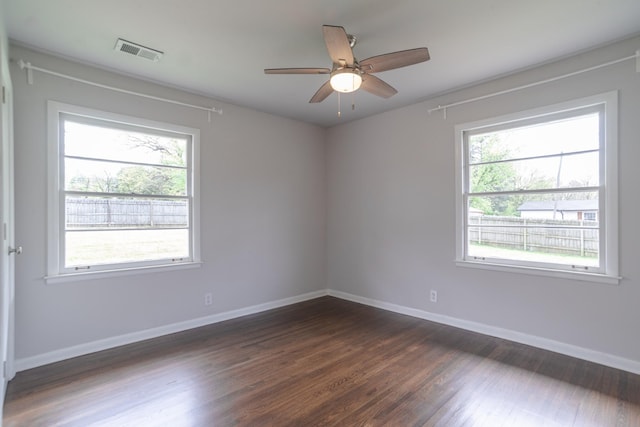spare room with baseboards, a ceiling fan, visible vents, and dark wood-style floors