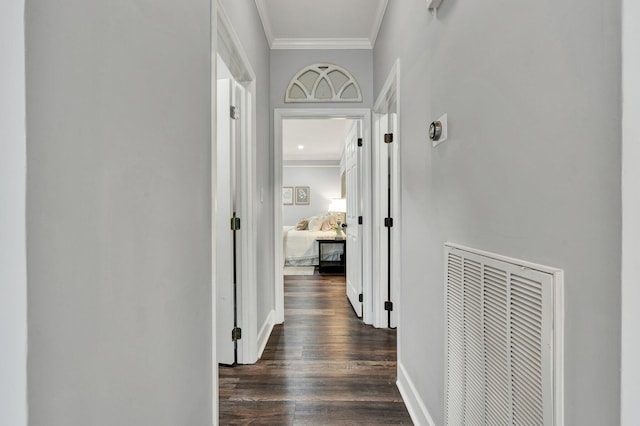 hall with dark wood finished floors, visible vents, baseboards, and ornamental molding