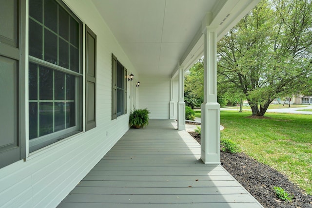 wooden terrace featuring a lawn and a porch