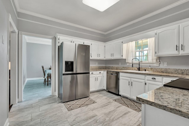 kitchen featuring white cabinets, ornamental molding, a sink, light stone countertops, and appliances with stainless steel finishes