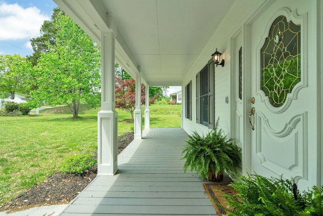 wooden terrace featuring covered porch and a yard