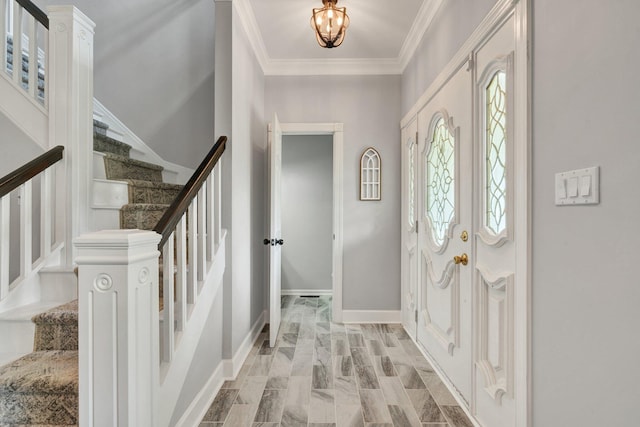 foyer with baseboards, stairs, ornamental molding, and an inviting chandelier