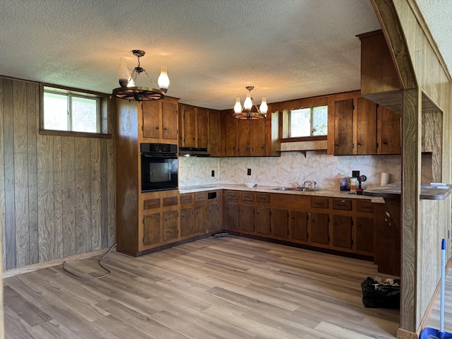 kitchen featuring a chandelier, backsplash, light countertops, and oven