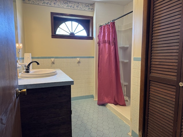 bathroom featuring a wainscoted wall, tile walls, a shower with shower curtain, a closet, and vanity