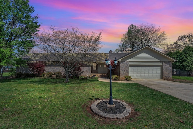 ranch-style home featuring driveway, a chimney, brick siding, an attached garage, and a yard
