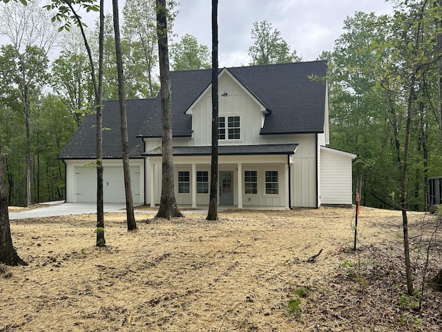 modern farmhouse style home with board and batten siding, driveway, roof with shingles, and a garage