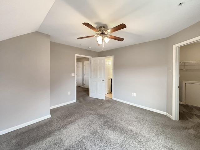 unfurnished bedroom with a walk in closet, baseboards, a ceiling fan, and carpet