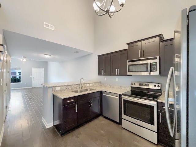 kitchen with a sink, baseboards, a peninsula, appliances with stainless steel finishes, and visible vents