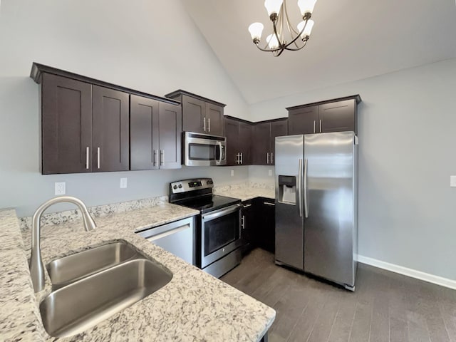 kitchen featuring stainless steel appliances, dark brown cabinets, wood finished floors, a sink, and a chandelier