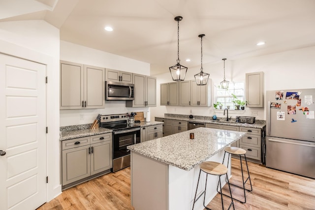 kitchen with light wood-type flooring, a kitchen island, appliances with stainless steel finishes, and gray cabinets