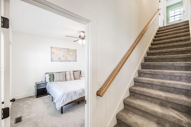 stairway featuring baseboards, a ceiling fan, visible vents, and carpet flooring