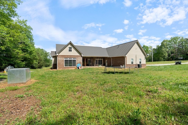 703 Gaither Hinson Rd, Waynesboro, TN 38485 - rear view of property with brick siding, a trampoline, and a lawn