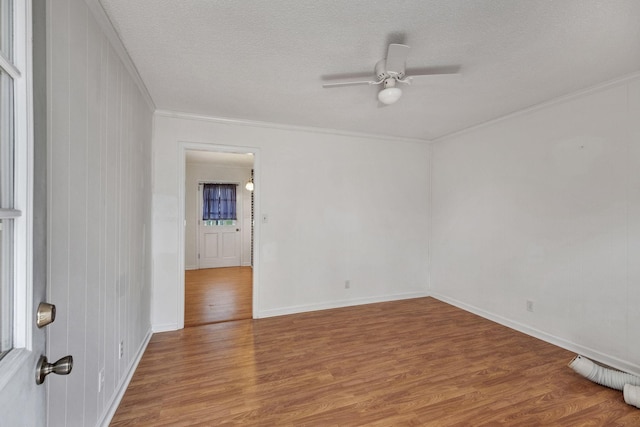 spare room with wood finished floors, a textured ceiling, ornamental molding, and ceiling fan