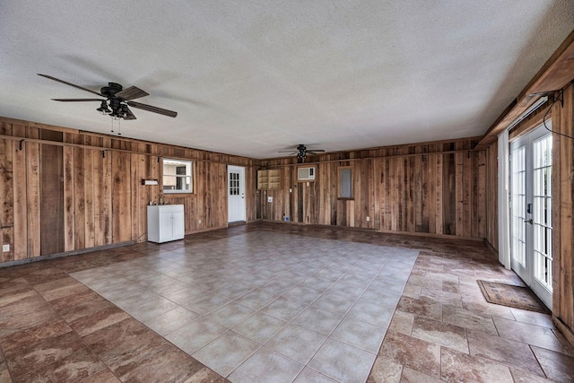 spare room featuring plenty of natural light, wood walls, and ceiling fan
