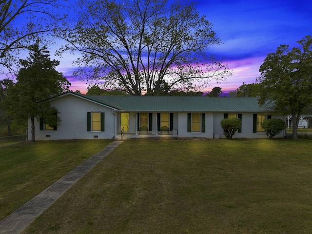 ranch-style house featuring brick siding, a front yard, covered porch, and metal roof