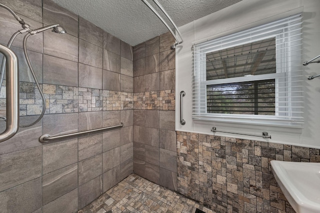 full bath with a tile shower, tile walls, a textured ceiling, and a wainscoted wall