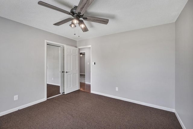 unfurnished bedroom featuring baseboards, dark carpet, and a closet