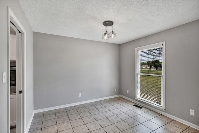 spare room featuring a textured ceiling, light tile patterned flooring, a chandelier, baseboards, and visible vents