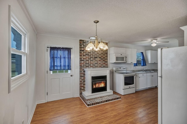kitchen featuring white cabinets, a textured ceiling, light wood finished floors, and white appliances