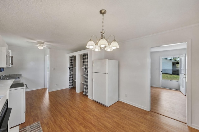 interior space with ceiling fan with notable chandelier, light wood-style flooring, baseboards, and ornamental molding