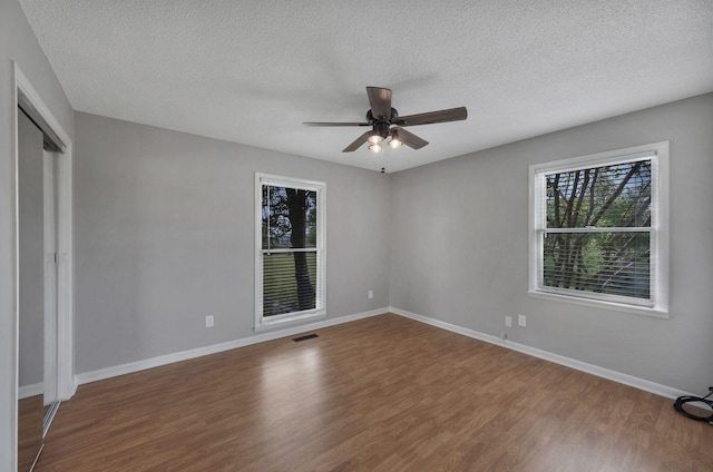 unfurnished bedroom with baseboards, wood finished floors, visible vents, and a textured ceiling