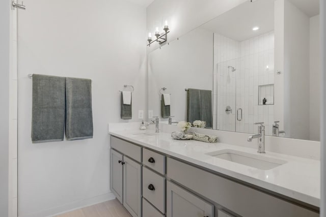 bathroom featuring a shower stall, baseboards, a sink, and double vanity
