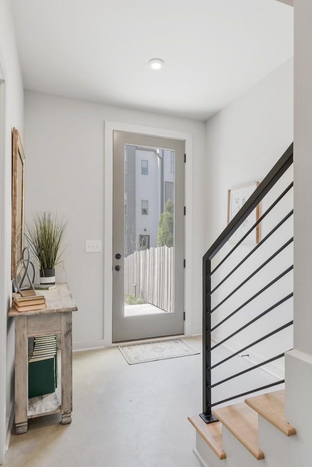 foyer entrance with stairway, finished concrete floors, and recessed lighting