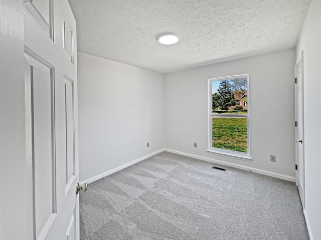 spare room featuring visible vents, baseboards, carpet, and a textured ceiling