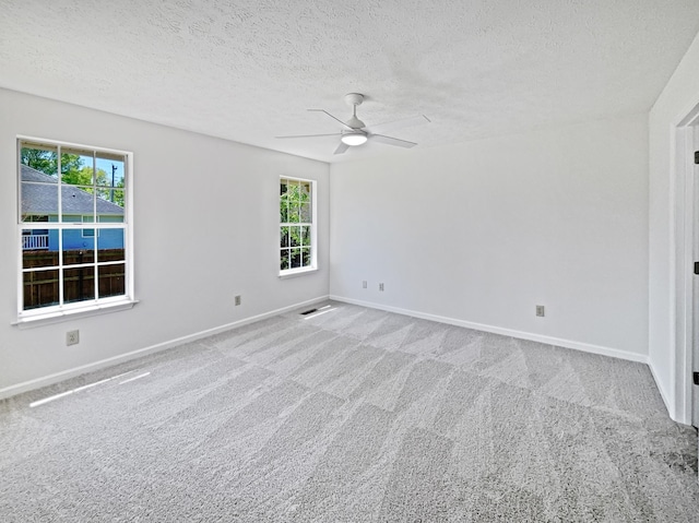 carpeted empty room featuring plenty of natural light, a ceiling fan, and baseboards